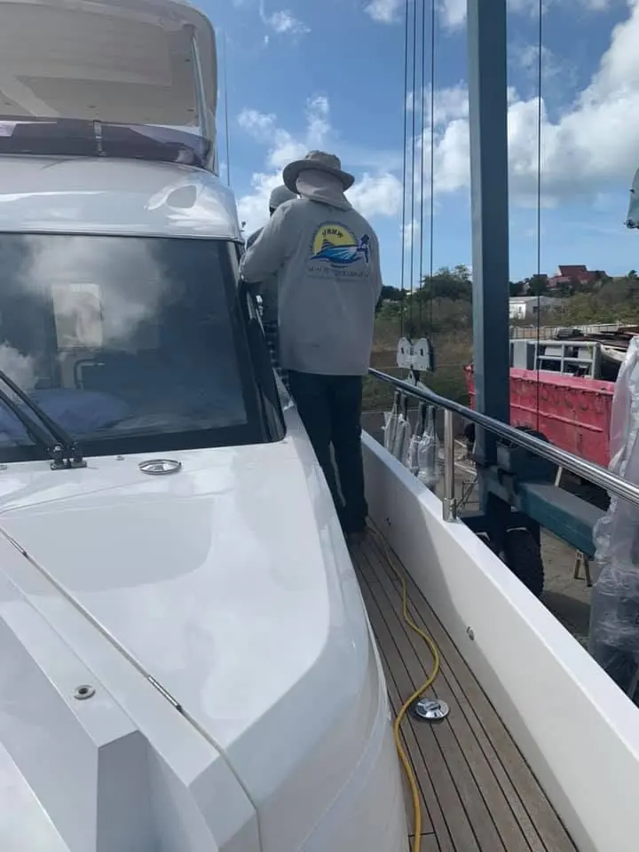 Crew polishing the dark blue hull of M/Y Paladin in Simpson Bay — SXM Refinishing