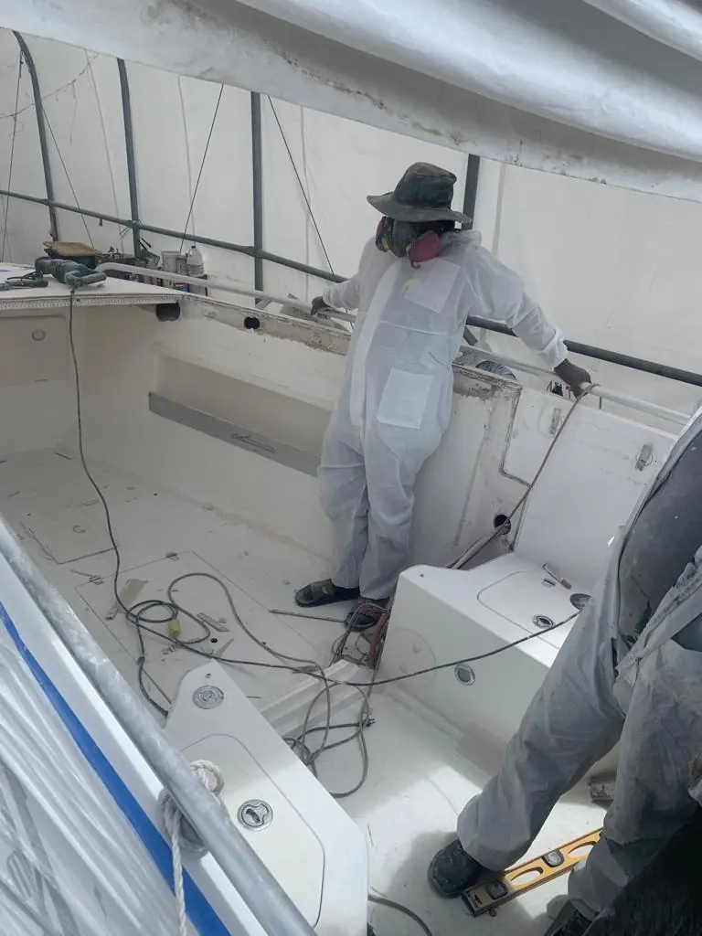 Technician in protective coveralls sanding a cockpit interior by SXM Refinishing in St. Maarten