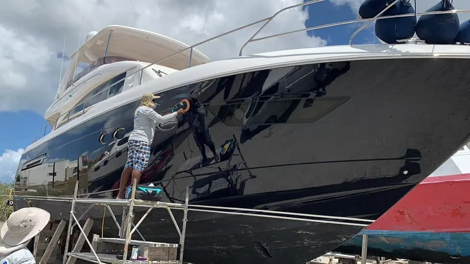 Boat refinishing craftsman wet-sanding a yacht hull by SXM Refinishing in St. Maarten