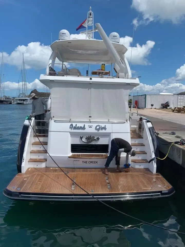 Refinishing specialists inspecting a yacht hull by SXM Refinishing in St. Maarten