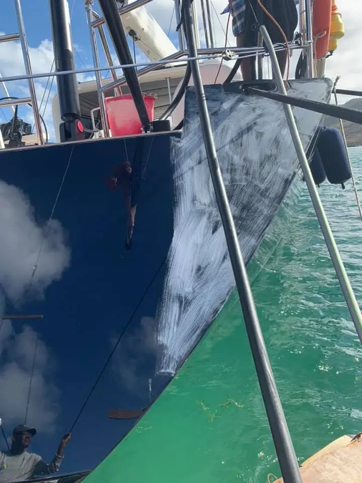 Barrier coat being applied to a navy sailing yacht hull by SXM Refinishing in St. Maarten