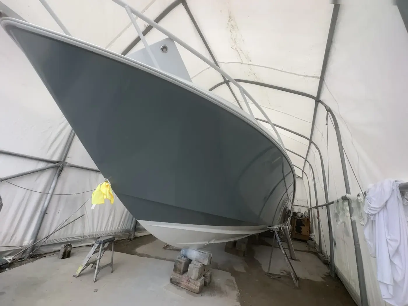 Freshly painted grey hull gleaming inside the covered spray tent by SXM Refinishing in St. Maarten